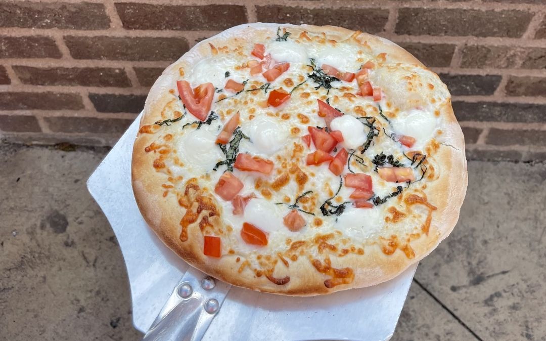Fresh wood-fired Margherita pizza served at the Willow Brook Village courtyard in Delaware, Ohio, where senior residents enjoy outdoor dining and community events.